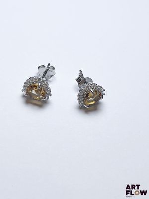 une paire de boucles d'oreilles en diamants jaunes et blancs posées sur un fond blanc