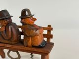 two wooden figurines sitting on a wooden bench