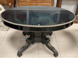 une table noire avec un plateau en verre, posée sur un sol carrelé