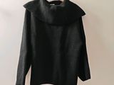 Le pull est suspendu à un cintre accroché au mur.