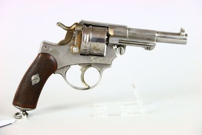 un vieux revolver avec une poignée en bois sur une surface blanche