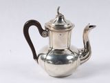 an antique silver tea pot with a wooden handle on a white surface