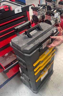 un homme debout à côté d'un chariot à outils sur lequel se trouvent des outils