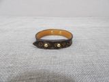 a close up of a brown leather bracelet on a white surface