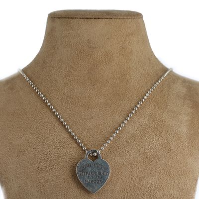 un gros plan d'un collier orné d'un cœur, porté par un mannequin