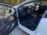 the interior of a white car with its door open and the driver ' s seat down