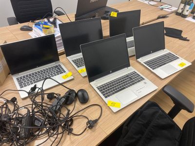 quatre ordinateurs portables posés sur une table, entourés de câbles