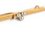 a close up of a gold tie bar with pearls on it