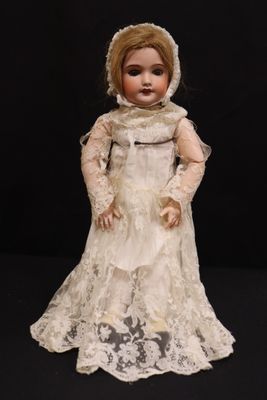 an old fashioned doll with a white dress and bonnet on a black background