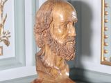 une statue représentant un homme barbu assis sur une table