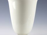 une image représentant un vase blanc posé sur un support métallique