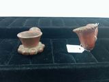 two small vases sitting on a black velvet surface