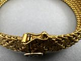 gold bracelet with a clasp on a white surface