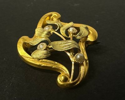 une image représentant une broche en or ornée de perles sur un fond noir
