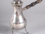 a silver coffee pot with a wooden handle on a stand