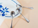 two spoons sitting on a plate with a blue and white floral design
