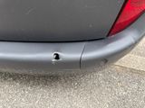 the rear end of a car with a hole in the bumper