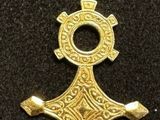 an image of a gold cross pendant on a black surface