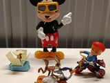 mickey mouse figurines are sitting on a table next to a toy boat