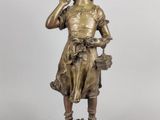 an antique bronze statue of a boy with a basket of flowers