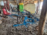 un tracteur et une charrue rangés dans une grange