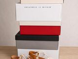 une paire de sandales blanches posée sur une pile de cartons