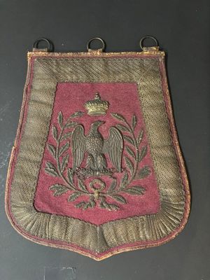 un vieux sac rouge et or brodé, orné d'un oiseau