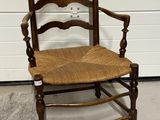 une chaise en bois avec une assise tressée et des accoudoirs
