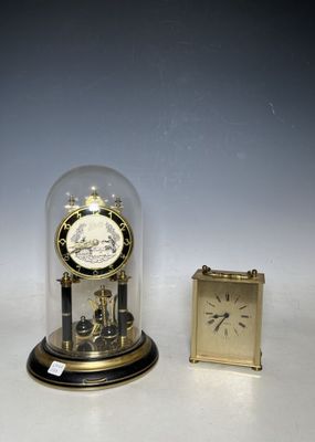 a small clock sitting under a glass dome next to a small clock