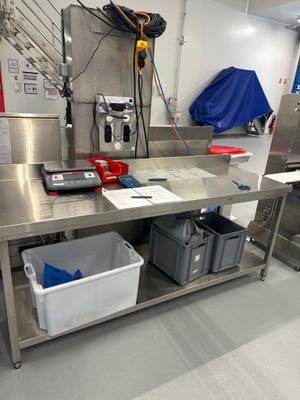 une grande table de travail en acier inoxydable équipée de deux bacs