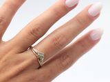 the hand of a woman with a white manicured nails and a gold ring with a green stone