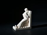 une sculpture blanche représentant un homme assis sur un banc