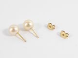a pair of pearl stud earrings and a pair of gold stud earrings
