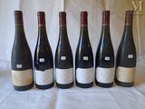 six bottles of wine are lined up in a row on a table