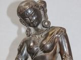bronze statue of a woman sitting on the ground with her legs crossed