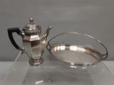 une théière en argent et un bol en argent posés sur une table en verre