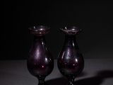 pair of purple glass vases sitting on top of a table