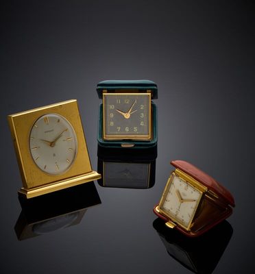 three different clocks sitting on top of a table next to each other