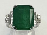 gros plan d'une bague avec une pierre verte entourée de diamants