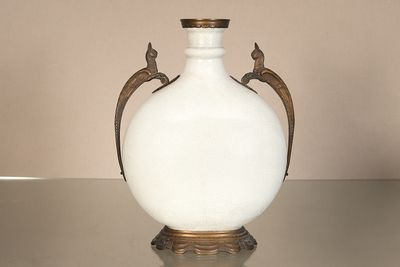 un vase blanc posé sur une table, sur lequel sont perchés deux oiseaux