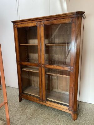 une vieille armoire en bois avec des portes vitrées et des étagères, dans une pièce