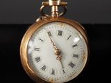 a gold pocket watch with roman numerals on the face