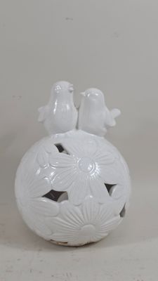 a white vase with two birds sitting on top of it