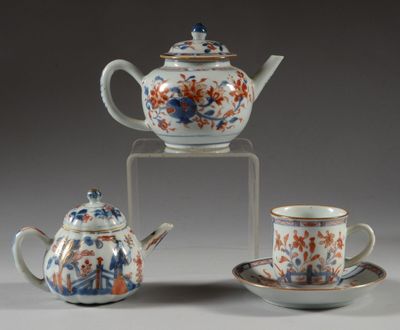 three teapots and two cups sitting on a table