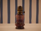 a red glass bottle with a gold top on a table