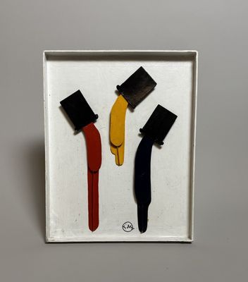 trois objets de couleurs différentes dans une boîte blanche posée sur une surface blanche