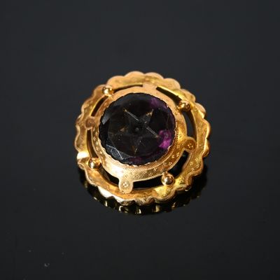 un gros plan d'une bague en or ornée d'une pierre violette au centre