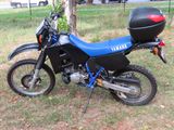 une moto bleue et noire garée dans l'herbe