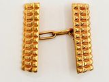 an image of a pair of gold tone cufflinks on a white surface