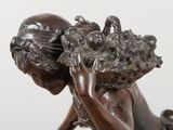 bronze statue of a boy with a basket of fruit on his head
